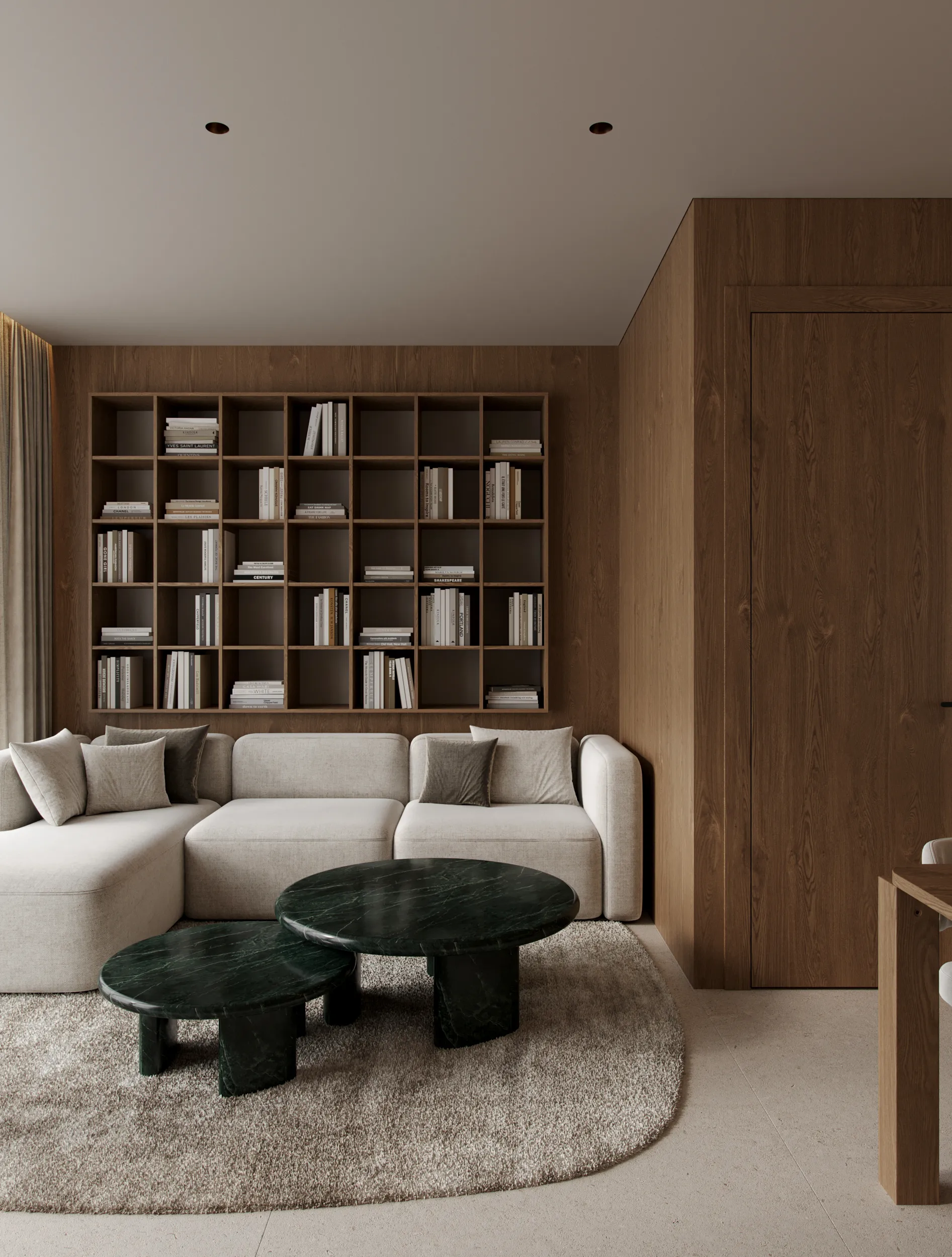 Mood apartment living room by Ishoro in Kaunas — full-height oak bookshelves, a cream modular sofa and nested green-marble tables